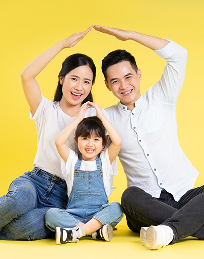 Parents and their young child sitting together against a yellow background
